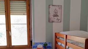 A room with a bunk bed, a desk with a chair, a window with blinds, and a painting on an easel. - Elegant vacation home in the Gulf of Asinara, ideal for families. (Sorso)