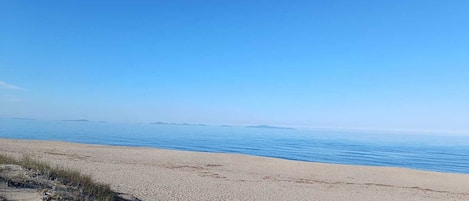 Ein Strand mit blauem Himmel und ruhiger See.