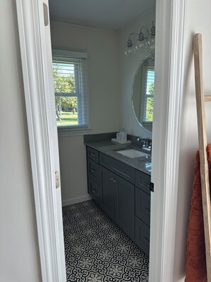A bathroom with a window, a sink, and a mirror. - Spacious 4-bedroom house in perfect Murfreesboro with AC (Murfreesboro)