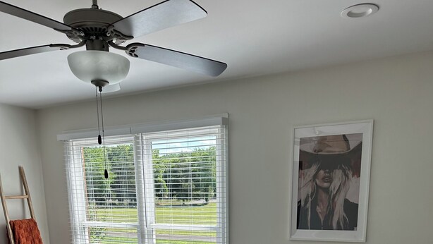 A bedroom with a bed, white bedding, a ceiling fan, a window with blinds, a ladder, and a framed picture on the wall. - Spacious 4-bedroom house in perfect Murfreesboro with AC (Murfreesboro)