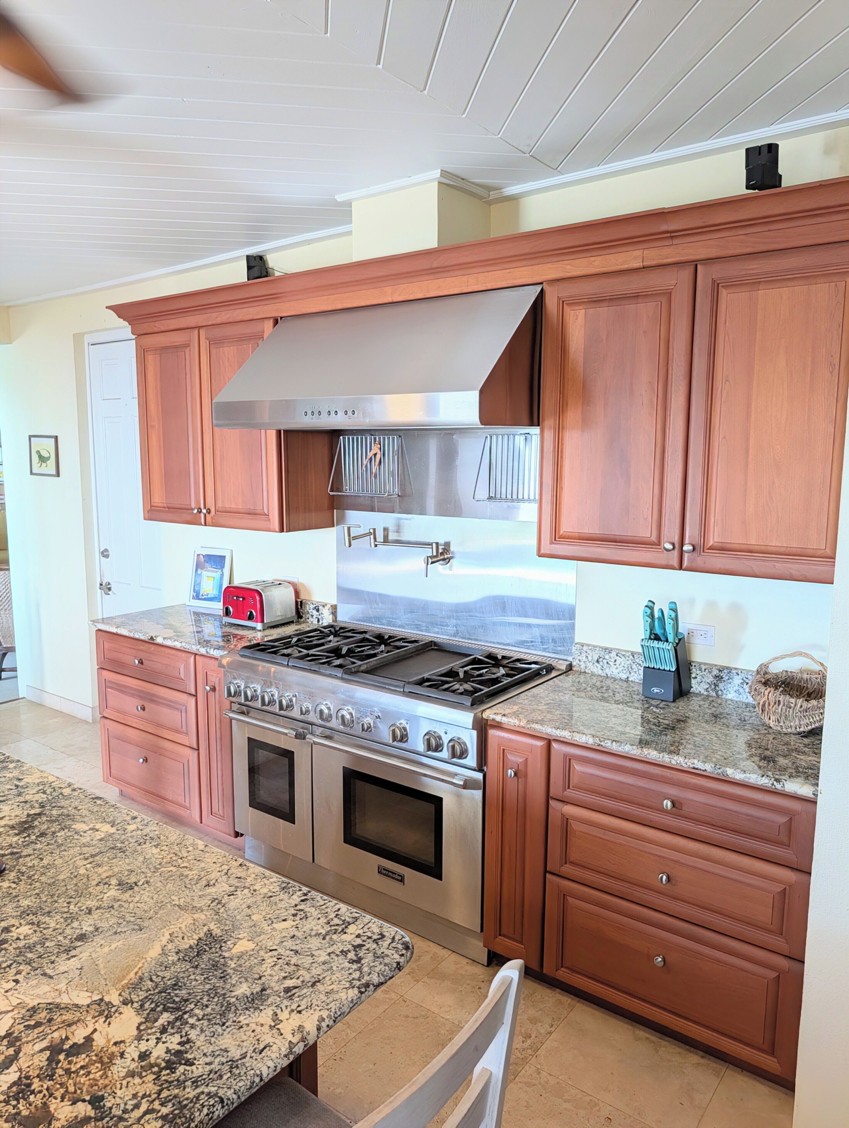 A kitchen with wooden cabinets, a stainless steel stove, and a granite countertop.