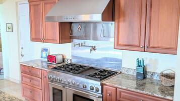 A kitchen with wooden cabinets, a stainless steel stove, and a granite countertop.