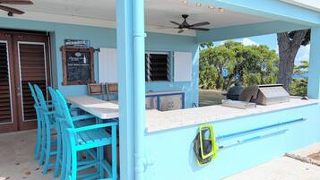 Un espace extérieur abrité avec des chaises bleues, un comptoir et un barbecue.