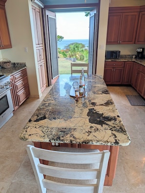 A kitchen with a large island, wooden cabinets, and a view of the ocean.