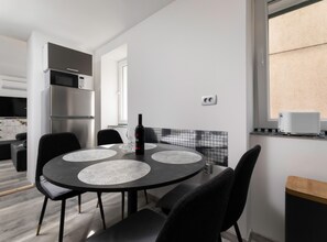 A modern kitchen with a dining table, chairs, a wine bottle, and a toaster. - Duplex One Bedroom Apartment (Punat)