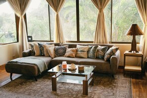 Ein Wohnzimmer mit einer Couch, einem Glastisch und einer Lampe.