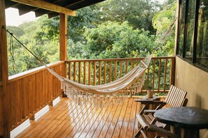 Eine Holzterrasse mit einer Hängematte, Holzstühlen und einem Tisch.