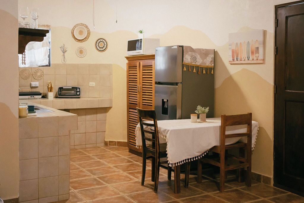 Una cocina compacta con mesa, sillas, refrigerador, microondas y tostadora.