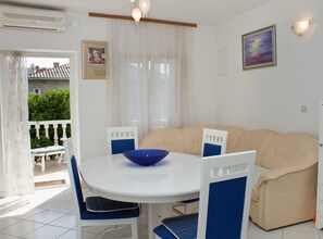 A dining area with a round table, chairs, a bowl, a sofa, and a window with curtains. - Four Bedroom Apartment with Sea View and Pool (Okrug Gornji)