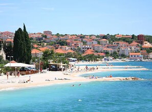 A coastal town with a beach, clear blue waters, and buildings with red roofs. - Four Bedroom Apartment with Sea View and Pool (Okrug Gornji)