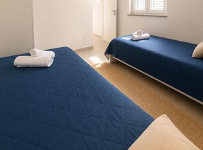 A hotel room with two beds, each with a blue bedspread and a rolled white towel. - Four Bedroom Apartment with Sea View and Pool (Okrug Gornji)