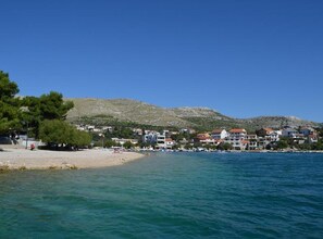A coastal town with buildings along the shore, a sandy beach, and a mountain in the background. - One Bedroom Apartmant with Sea View and Balcony (Šibenik)