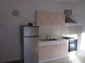 A kitchen with a refrigerator, sink, stove, and cabinets. - One Bedroom Apartment with Sea View and Garden (Šibenik)