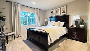A bedroom with a bed, bedside tables, a window with curtains, and a view of greenery outside. - Stylish SoCal Getaway - Relax & Unwind (Pomona)