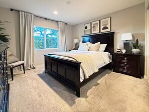 A bedroom with a bed, bedside tables, a window with curtains, and a view of greenery outside. - Stylish SoCal Getaway - Relax & Unwind (Pomona)