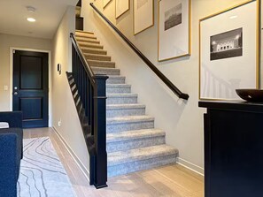 A staircase with carpeted steps and a handrail, leading to a dark door. - Stylish SoCal Getaway - Relax & Unwind (Pomona)