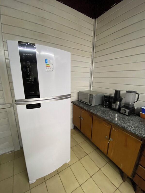 A kitchen with a white refrigerator, wooden cabinets, a microwave, a coffee maker, and a blender on the countertop.