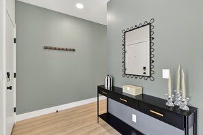 A modern bathroom with a black vanity, a mirror with a decorative frame, and a light switch on the wall.