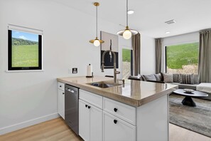 A modern kitchen with a built-in dishwasher, a sink, and a dining area with a table and chairs.