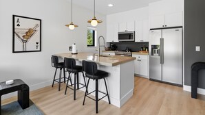 A modern kitchen with a central island, bar stools, a microwave, and a refrigerator. - The Upstate Loft- Close to Ithaca, Cornell, and IC (Newfield)