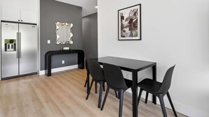 A modern kitchen with a built-in refrigerator, a black countertop, and a dining area with a table and chairs. - The Upstate Loft- Close to Ithaca, Cornell, and IC (Newfield)