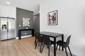 Eine moderne Küche mit integriertem Kühlschrank, schwarzer Arbeitsplatte und einem Essbereich mit Tisch und Stühlen.