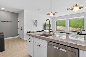 Een moderne keuken met een ingebouwde vaatwasser, een roestvrijstalen spoelbak en hanglampen.