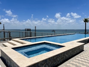 A rectangular infinity pool with a clear view of the ocean and a distant island. - Stunning Bay Views at Las Velas Village! (South Padre Island)