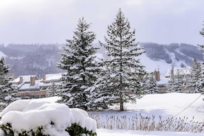 Un paisaje nevado con un imponente árbol de hoja perenne y un edificio con tejado cubierto de nieve.