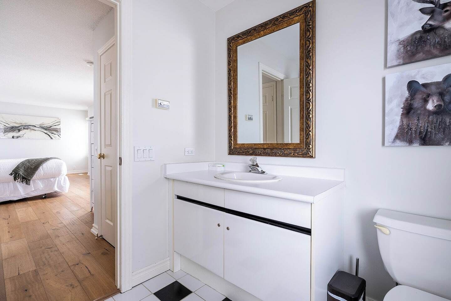 A bathroom with a white sink, a gold-framed mirror, and a toilet.