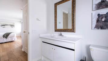 A bathroom with a white sink, a gold-framed mirror, and a toilet.