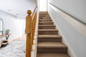 A staircase with wooden balusters and carpeted steps leading to a landing.