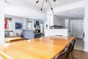 Amplia sala de estar con una mesa de comedor de madera, un sofá gris y una chimenea.