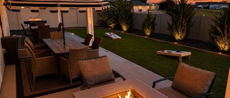 An outdoor patio with a fire pit, seating, and a covered area.