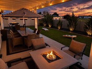 An outdoor patio with a fire pit, seating, and a covered area. - Arcade • Covered Patio • Fire pit • Sleeps 10 (Nampa)
