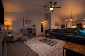 A modern living room with a sofa, coffee table, and a ceiling fan. - Arcade • Covered Patio • Fire pit • Sleeps 10 (Nampa)