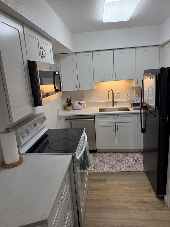 A modern kitchen with white cabinets, stainless steel appliances, and a patterned rug.