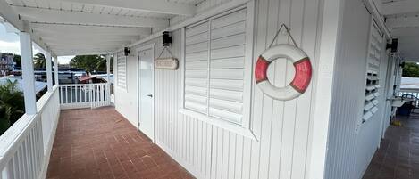 A covered porch with a tiled floor, white railings, and a lifebuoy hanging on the wall.