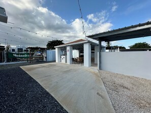 An outdoor patio area with a concrete floor, a covered seating area, and a white wall. - Perfect 7-bedroom building with AC, private pool, generator, cistern in Combate (Combate)