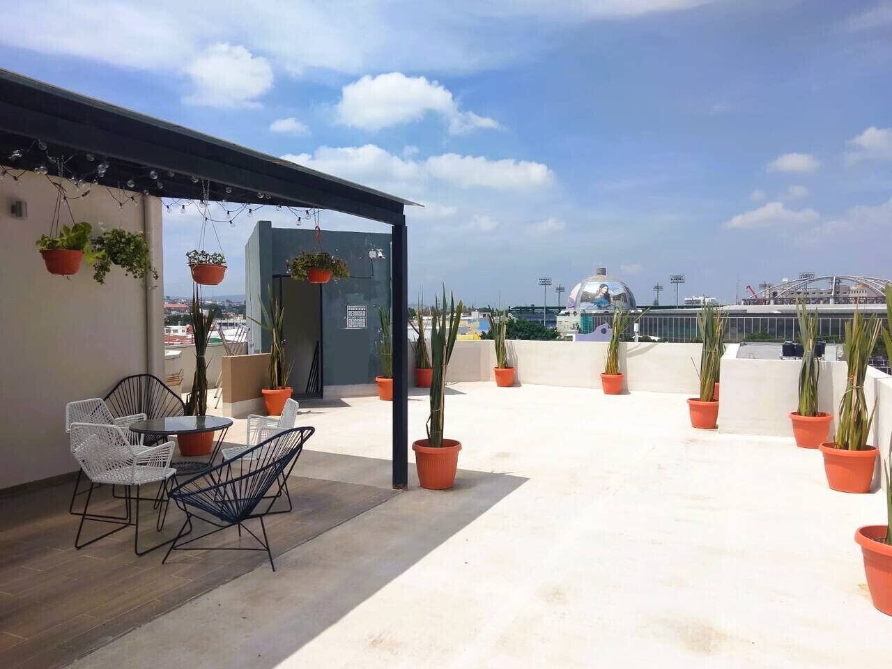 A rooftop terrace with outdoor seating, potted plants, and a view of the cityscape.