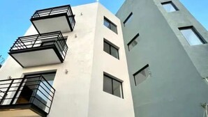 Un edificio moderno con facciata bianca, diversi balconi e un'autorimessa.