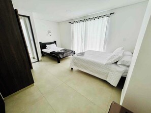 A bedroom with two beds, a door, and a window with curtains. - Casa de Lujo en Alcalá - Jacuzzi y Conectividad (Alcalá)