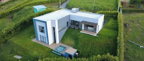 A modern two-story house with a large patio and a swimming pool.