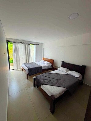 Ein Schlafzimmer mit zwei Betten, einer Schiebetür zum Balkon und einer weißen Decke.
