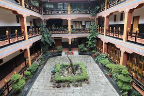 Un atrio de varios niveles con un patio central, plantas en macetas y una fuente.