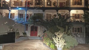 Un edificio de varios pisos con balcones, un patio central y plantas en macetas.