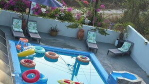Una piscina con juguetes inflables, sillas de descanso y plantas en macetas.