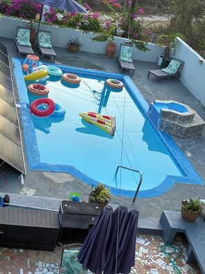 Ein Schwimmbecken mit aufblasbaren Spielzeugen, Liegestühlen und Topfpflanzen.