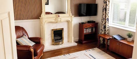 A living room with leather sofas, a fireplace, a television, and a bookshelf.