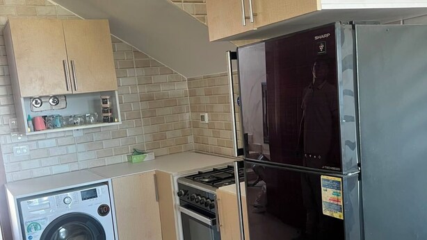 A compact kitchen with a washing machine, a stove, and a refrigerator.